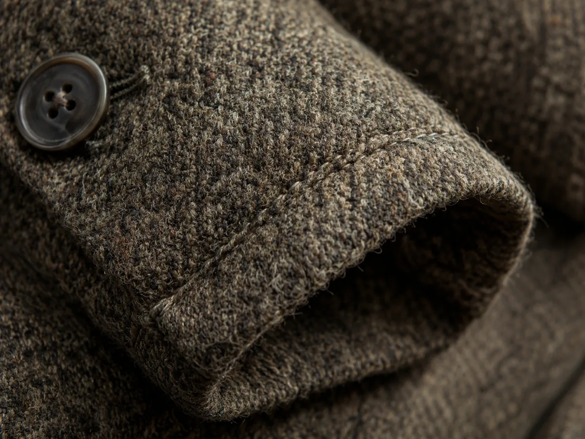 Close-up of a woven wool coat cuff showing individual fibres and a line of stitching
